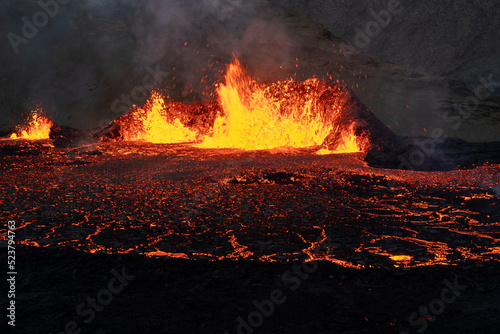 Volcano eruption at Meradalir near Fagradalsfjall, Iceland. Erupting magma and flowing lava at night.