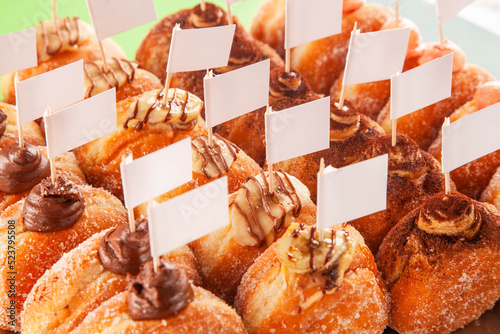 Dummy white flags placed on top of a variety of bombolone doughnuts freshly made at a bakery. photo