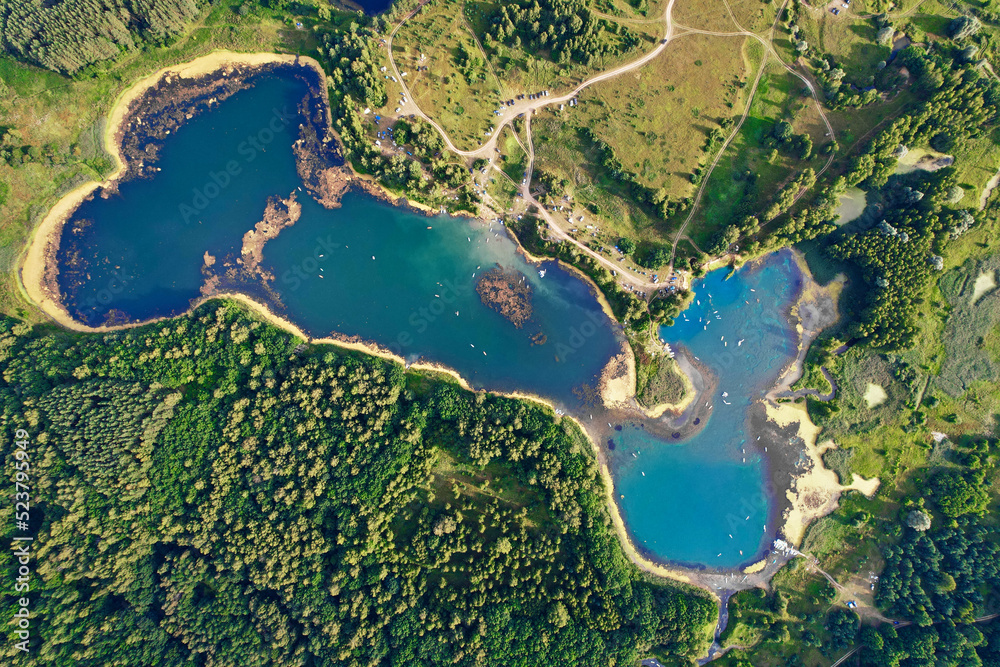Aerial view of blue forest wild lake with people on floating sup boards. Top view from drone