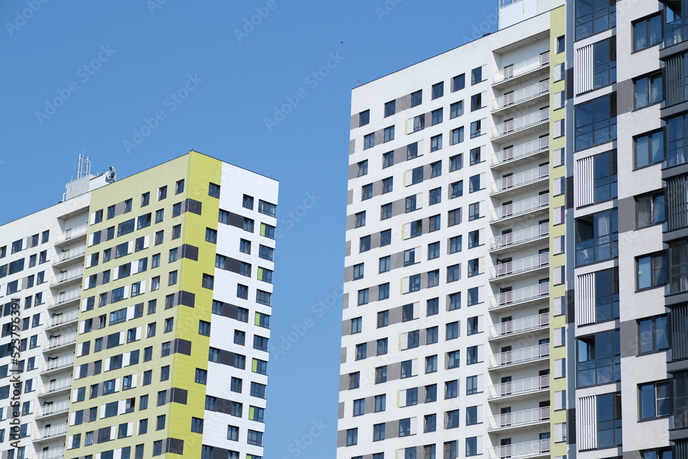 Facade of modern building in city. From below of contemporary high rise buildings with glass mirrored windows against cloudless blue sky.