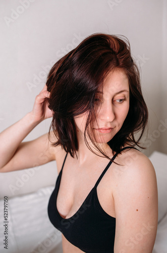 Portrait of a young beautiful brunette lying in bed wearing underwear