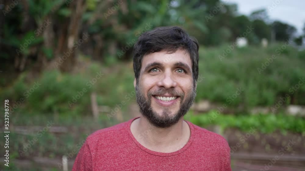 Portrait of a young man walking forward toward camera. Person walks in green agriculture farmland smiling Portrait of a young man walking forward toward camera. Person walks in green agriculture farmland smiling