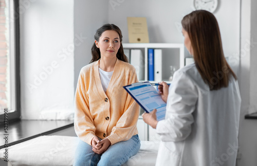 medicine, healthcare and people concept - female doctor with clipboard talking to woman patient at hospital
