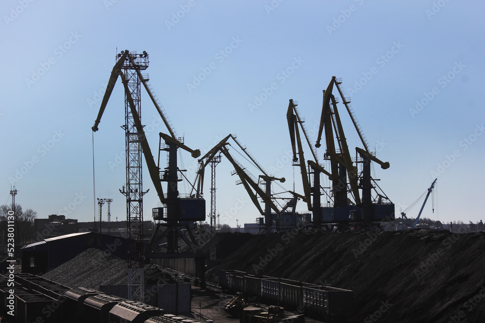silhouettes of cranes on mountains of coal in Port or logistics hub silhouettes of cranes on mountains of coal in Port or logistics hub