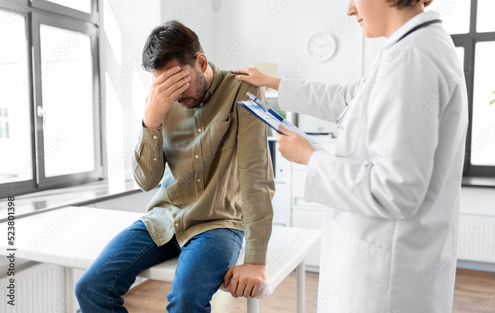 Fototapeta premium medicine, healthcare and people concept - female doctor with clipboard comforting sad male patient having health problem at hospital