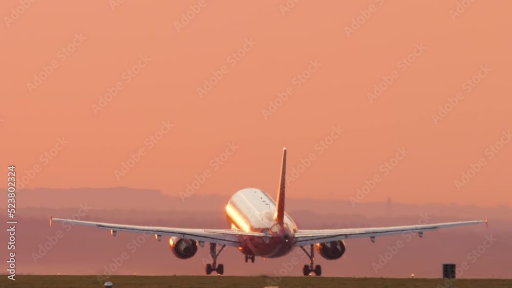 Cinematic footage of a jet plane taking off and climbing into the sunset. Picturesque sunset and flying away airliner. Tourism and travel concept, modern aviation