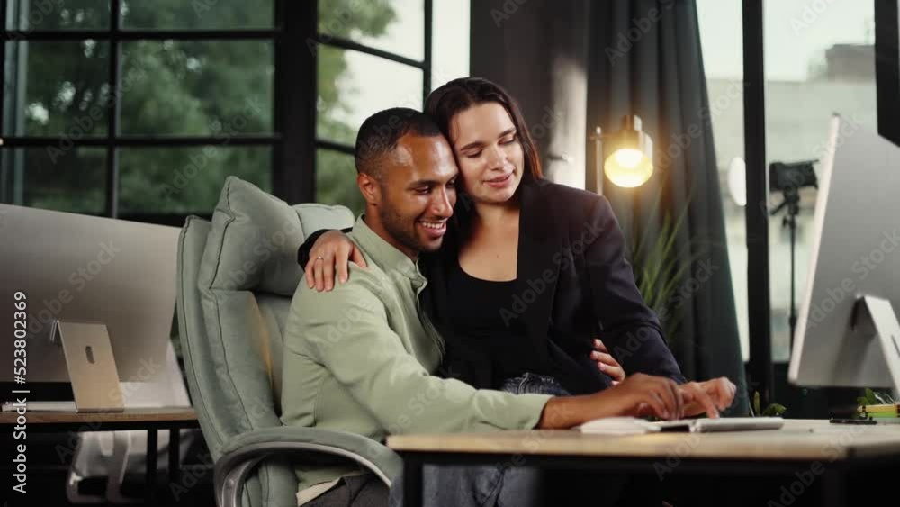 Happy young interracial couple work together in the office. Smiling couple enjoying each other in work time. Happy young interracial couple work together in the office. Smiling couple enjoying each other in work time.