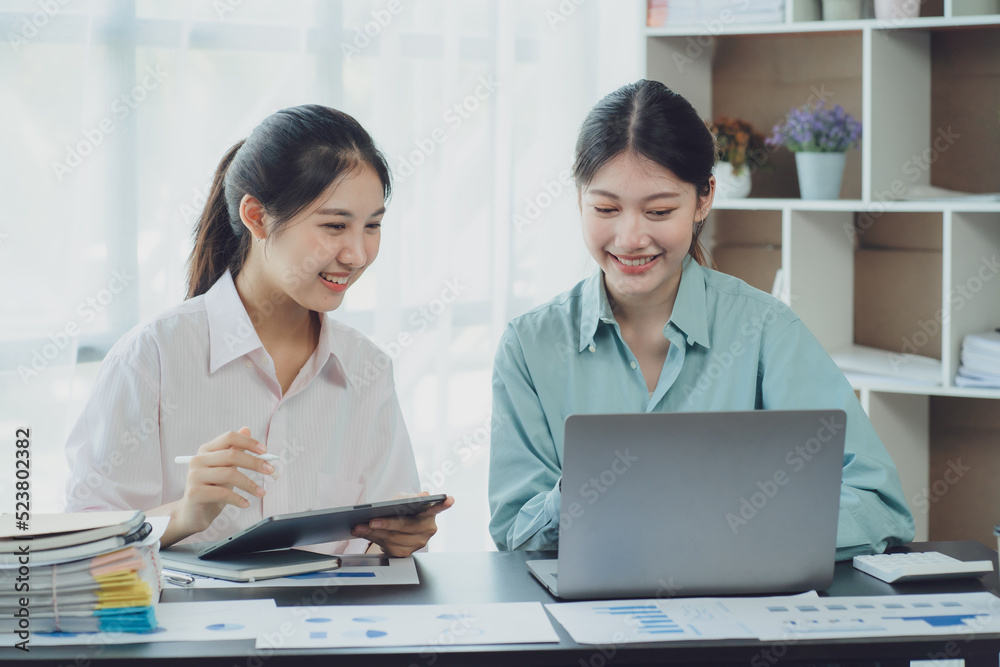 Smiling young Asian businesswomen talking to colleague and exchanging ideas together at office. Smiling young Asian businesswomen talking to colleague and exchanging ideas together at office.
