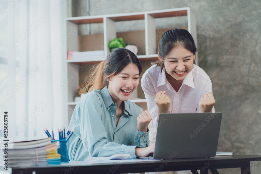 Two young Asian businesswoman discuss investment project working and planning strategy. Business people talking together with laptop computer at office. Two young Asian businesswoman discuss investment project working and planning strategy. Business people talking together with laptop computer at office.