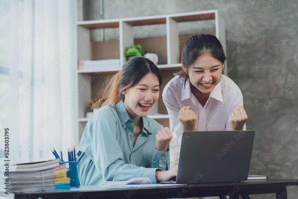 Two young Asian businesswoman discuss investment project working and planning strategy. Business people talking together with laptop computer at office. Two young Asian businesswoman discuss investment project working and planning strategy. Business people talking together with laptop computer at office.