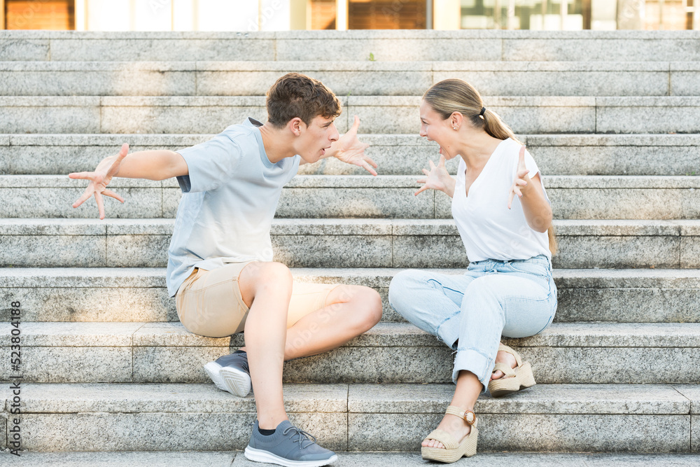 Teenager couple discussion. Toxic relationship concept. Boy and girl shouting sitting on stairs. Teenager couple discussion. Toxic relationship concept. Boy and girl shouting sitting on stairs.