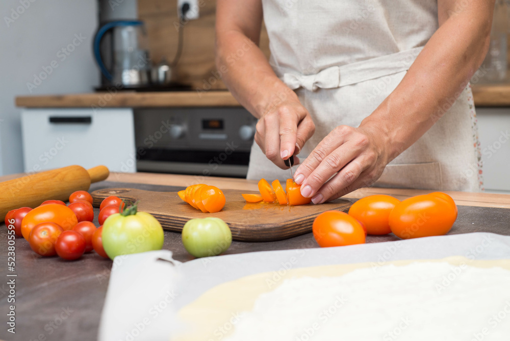 Woman hands are cutting tomatoes on slices. Preparation of pizza. Woman hands are cutting tomatoes on slices. Preparation of pizza.