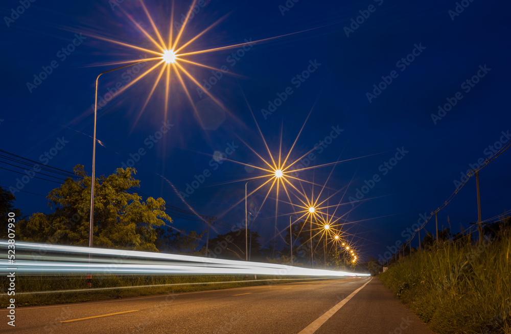 Low angle view of the car lights and starlight from roadside lamp posts from long exposure.