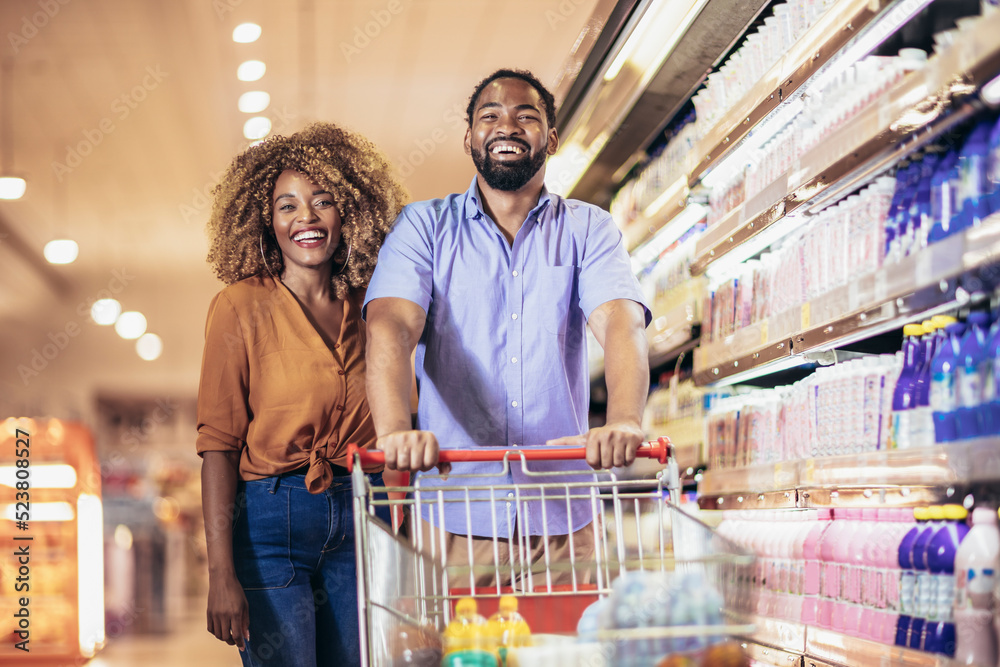 African American couple with trolley purchasing groceries at mall