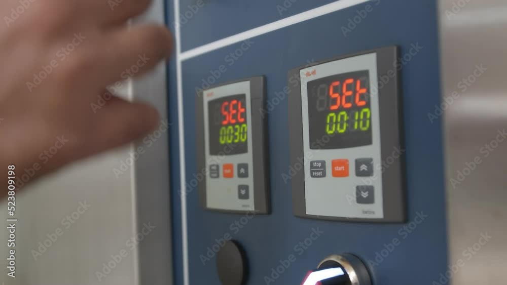 Close-up of male hands setting time and temperature on the industrial bread oven control panel Close-up of male hands setting time and temperature on the industrial bread oven control panel