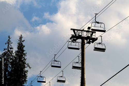 Empty chairs of the cableway at the mountain resort in a sunset
