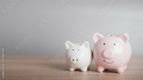 Two Piggy bank on wood table in gray background with copy space for text. Growth, saving budget and financial investment for retirement rich concept.