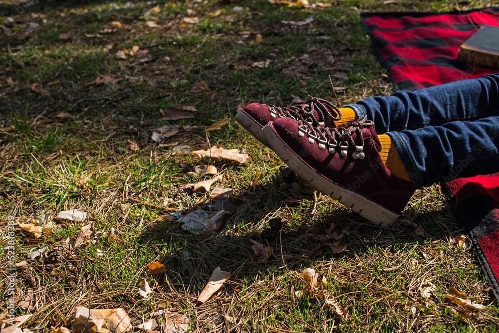 Resting on the grass. Stylish suede shoes on women’s legs. Burgundy shoes and yellow socks. Beautiful shoes on women’s legs. beautiful weekend