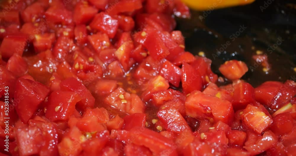 Pieces of tomatoes are fried in a pan. Pieces of tomatoes are fried in a pan.