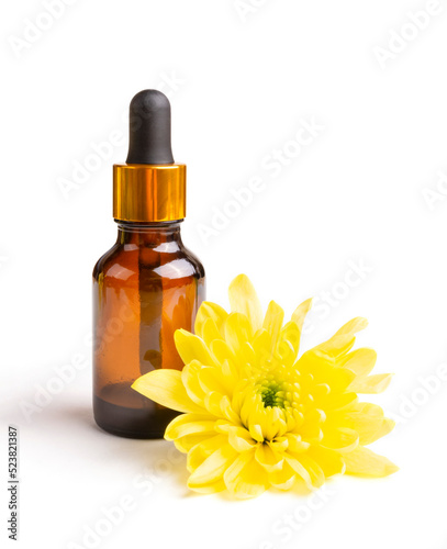 Essential oil of yellow chrysanthemum flower in a dark (brown) bottle with a pipette (bubble) on a white isolated background. Aromatherapy, spa. Oil for aroma lamps. Template for the design.