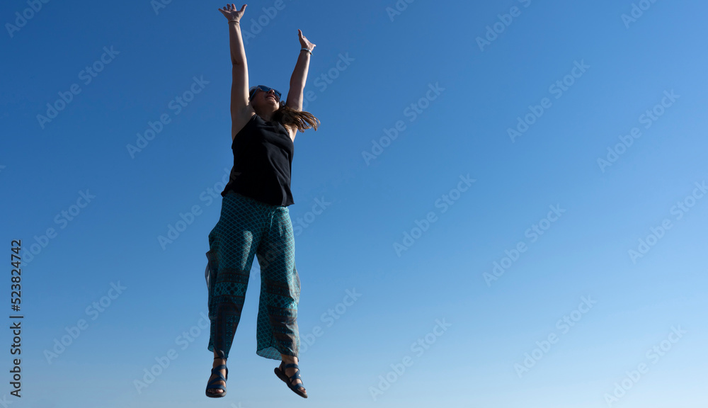 Smiling woman jumping with blue sky in the background Smiling woman jumping with blue sky in the background