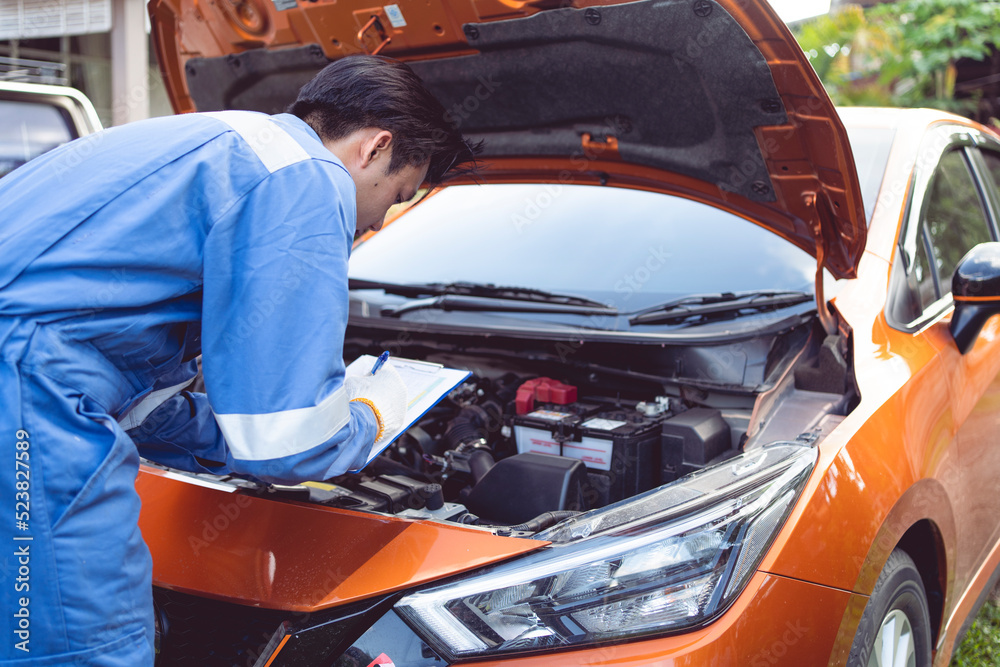 Fototapeta premium The mechanic is checking the condition of the car's engine. before delivering the car to the customer using a tablet and paper check list.
