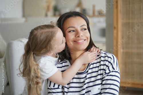 Portrait of family, kid hugs and kisses mom. Mother is smiling. Concept of affection and motherhood.