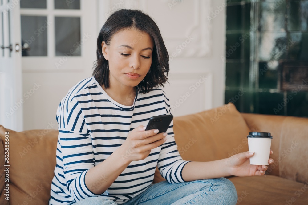 Happy young lady is texting on telephone. European woman having rest with cup of coffee at home. Happy young lady is texting on telephone. European woman having rest with cup of coffee at home.
