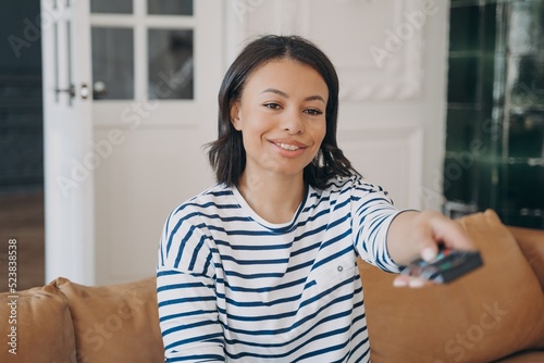 Smiling lady enjoying movie in living room. Happy spanish woman is watching television at home.