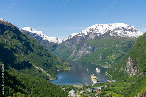 Geiranger Fjord and village Geiranger surrounded by high green and snowy mountains in Norway. © Jenni Ventura Martil