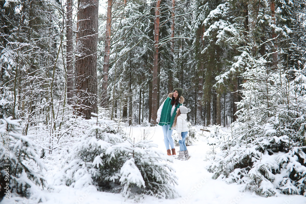 Young family for a walk. Mom and daughter are walking in a winter park.