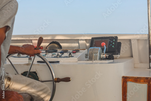 Hand of man on the steering wheel sailboat. Hands on the sailboat's steering wheel. Man's Hands with clocks Steering Wheel Of Yacht. Close-up of a man's hands on the yacht steering wheel. Helm yacht