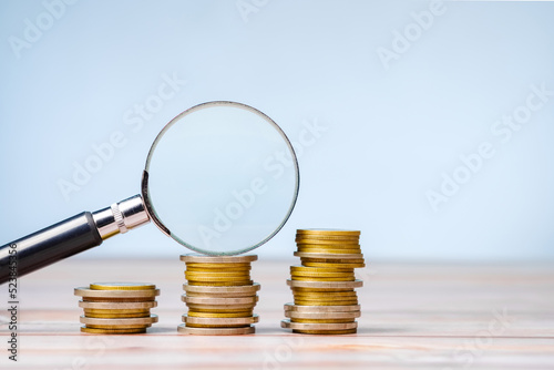 фотографія Magnifying glass on a few stacks of money coins that gradually increase, check t