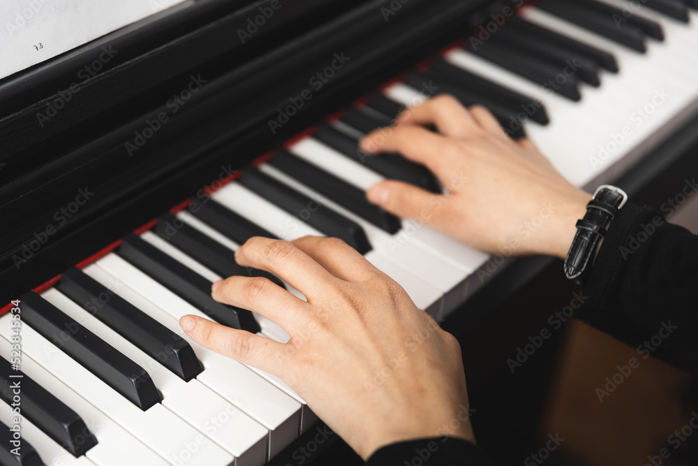 Close up of woman's hands playing piano by reading sheet music. Selective focus Close up of woman's hands playing piano by reading sheet music. Selective focus
