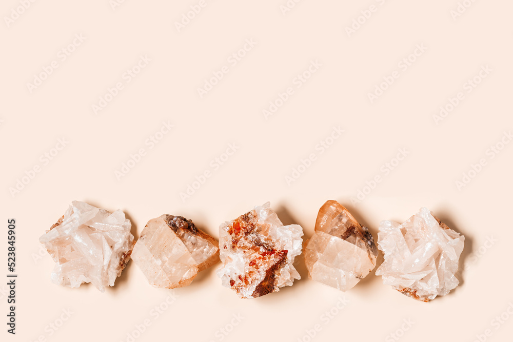 Flat lay bright beige quartz crystals on peach color background. Magic and healing crystal, gem stone, alternative medicine concept. Top view natural gemstone rock, quartz mineral - obrazy, fototapety, plakaty 