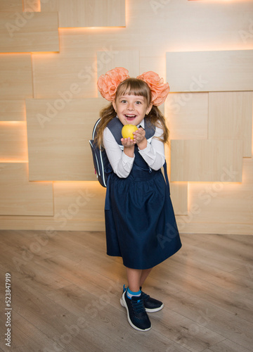 Back to school concept. happy Little girl schoolgirl with schoolbag holding tasty lunch green apple in her handin at classroom.elementary school. Education learning lessons for children photo