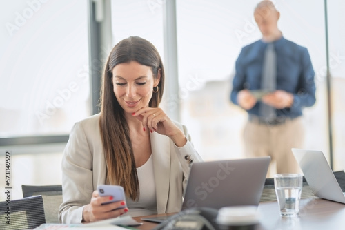 Businesswoman text messaging and using laptop while working at the office
