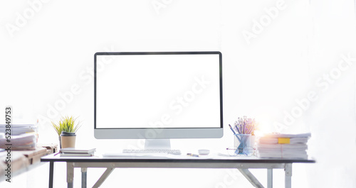 Laptop Computer, notebook, and eyeglasses sitting on a desk in a large open plan office space after working hours 