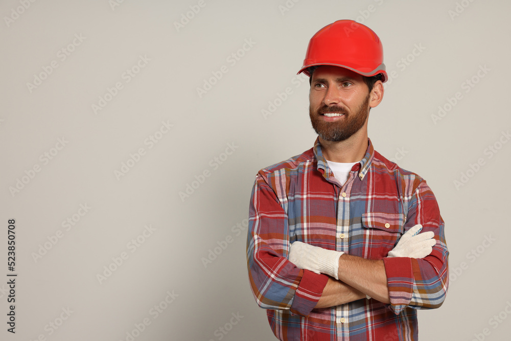 Professional builder in hard hat on light background, space for text