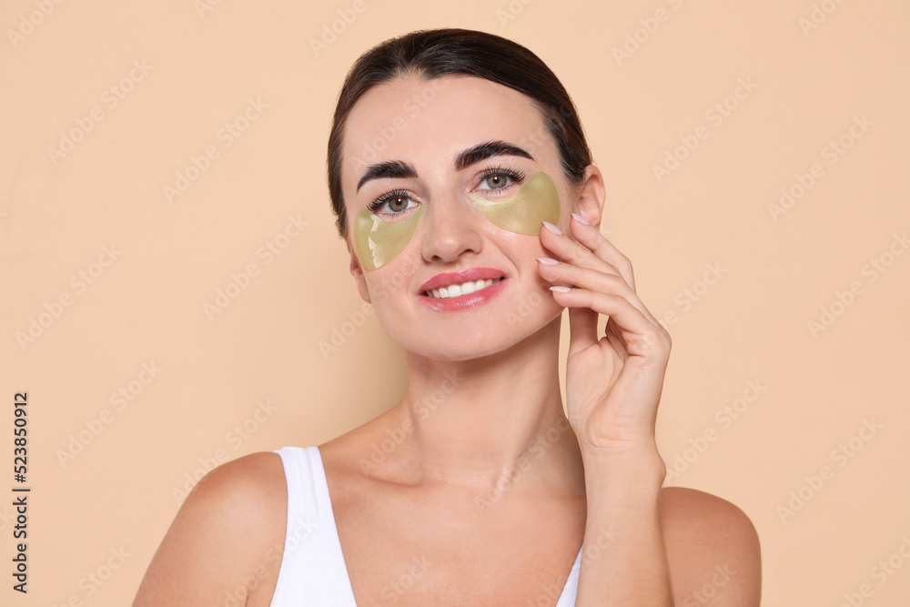 Beautiful woman with under eye patches on beige background