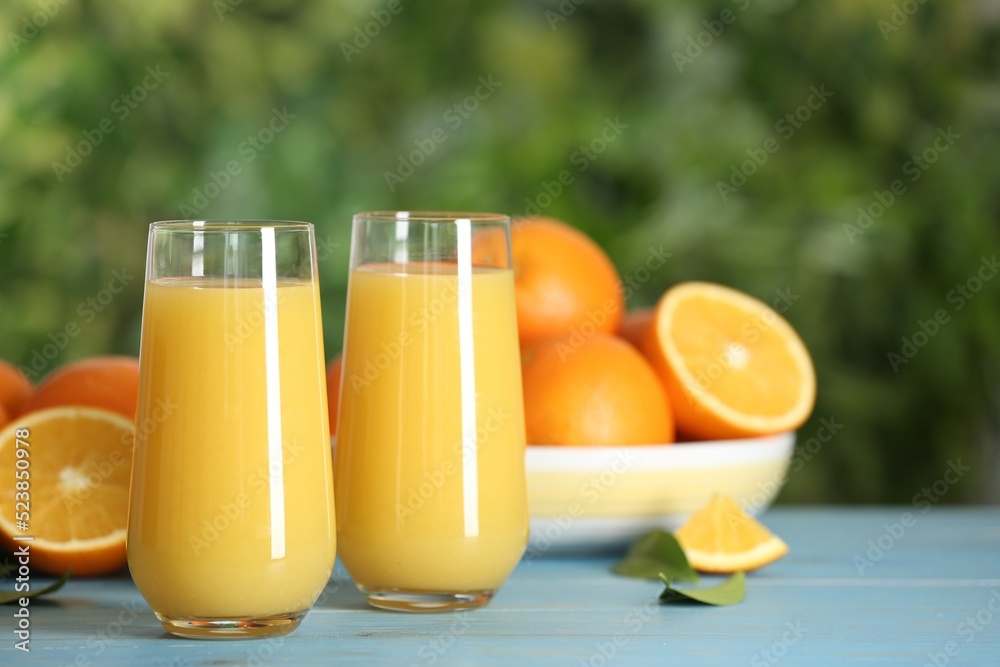 Delicious orange juice on light blue wooden table against blurred background. Space for text Delicious orange juice on light blue wooden table against blurred background. Space for text