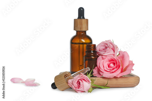 Bottles of essential rose oil and flowers on white background