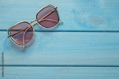New stylish sunglasses on turquoise wooden table, top view. Space for text