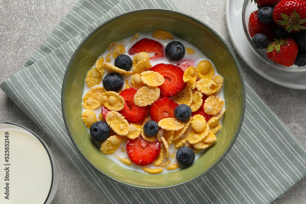 Corn flakes with berries in bowl served on grey table, flat lay Corn flakes with berries in bowl served on grey table, flat lay