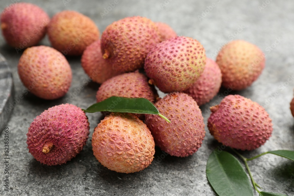 Fresh ripe lychee fruits on grey table, closeup