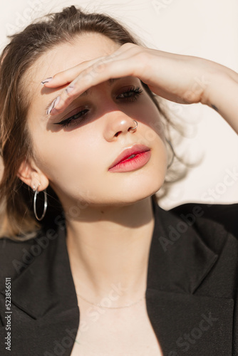 Fashion pretty young woman with black elegant vogue clothes sits outdoors in summer sunny day at sunlight