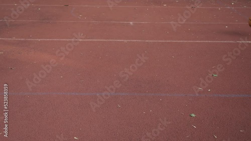 Basketball ball jumping through outdoor red street court by diagonal left to right
