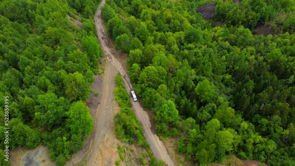 A dirt road in the mountains with a bus moving along it. Taken by a drone in the Khabarovsk Territory, a sunny area in the Far East of Russia. A dirt road in the mountains with a bus moving along it. Taken by a drone in the Khabarovsk Territory, a sunny area in the Far East of Russia.