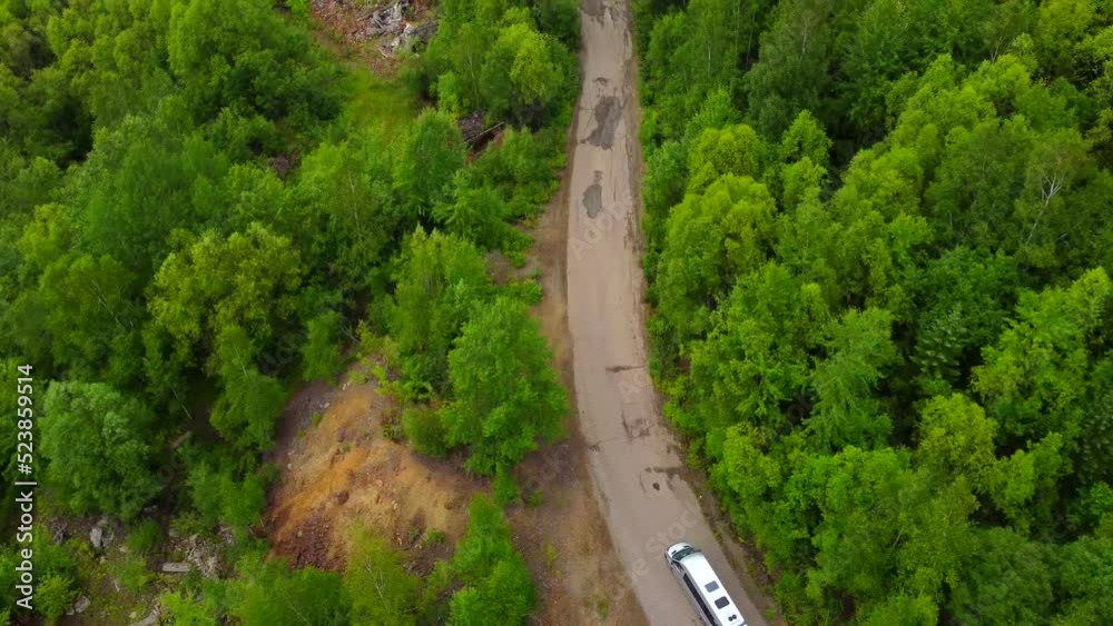 A dirt road in the mountains with a bus moving along it. Taken by a drone in the Khabarovsk Territory, a sunny area in the Far East of Russia. A dirt road in the mountains with a bus moving along it. Taken by a drone in the Khabarovsk Territory, a sunny area in the Far East of Russia.