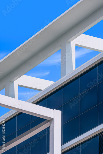 Abstract geometric pattern background of white deck rooftop structure of modern glass building against blue sky in vertical frame